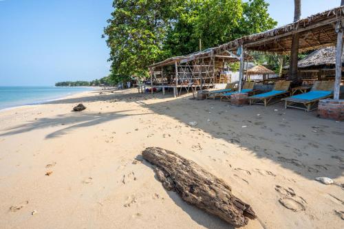 a beach with a building and a log on the sand at Isara Lanta Beach Resort in Ko Lanta