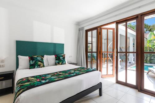 a bedroom with a large bed and a balcony at Villa Merah in Seminyak
