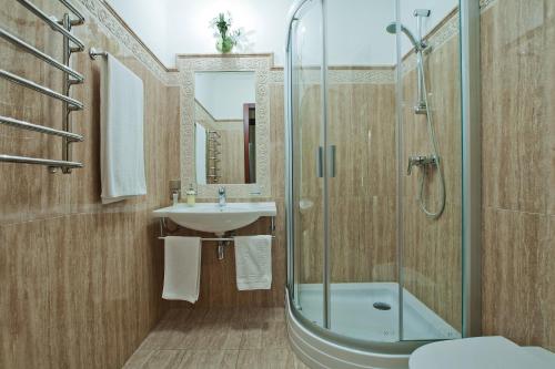 ein Bad mit einer Glasdusche und einem Waschbecken in der Unterkunft Hotel Helicopter in Krementschuk