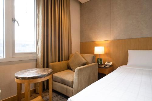 a hotel room with a bed and a chair at Stanford Hotel Seoul in Seoul