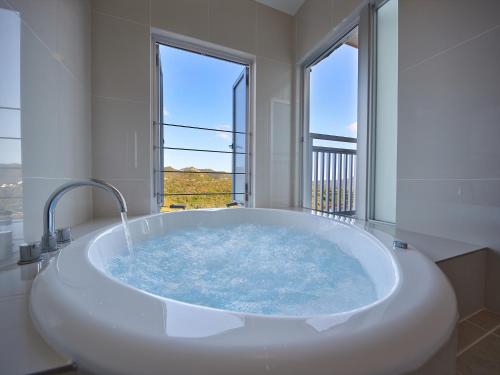 a large bath tub in a bathroom with windows at Hoshi No Terrace Motobu Yamazato in Motobu