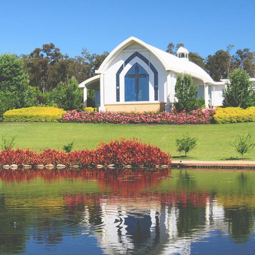 a house with a pond in front of a building at Hunter Valley Motel in Cessnock
