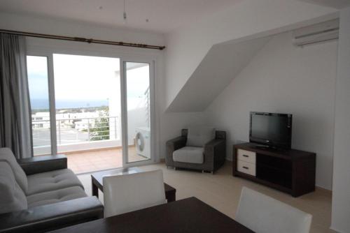 a living room with a tv and a couch and chairs at Penthouse With Breathtaking Panoramic Views of Mediterranean sea and Mountain in Akanthou