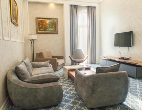 a living room with a couch and chairs in a hotel room at Promenade Hotel Baku in Baku