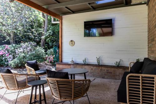 a patio with chairs and tables and a tv on the wall at Nest House Bright in Bright