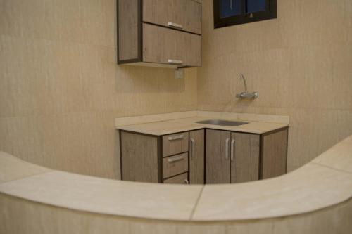 a kitchen with a sink and wooden cabinets at Al Eairy Apartment-Alqaseem 4 in Buraydah
