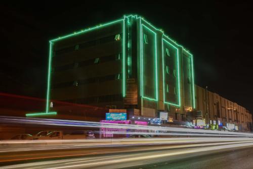 a building with green lights on the side of a street at Al Eairy Apartment-Alqaseem 4 in Buraydah