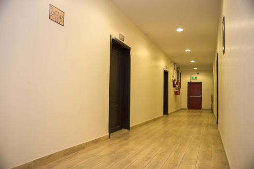 a hallway with black doors and wooden floors at Al Eairy Apartment-Alqaseem 4 in Buraydah