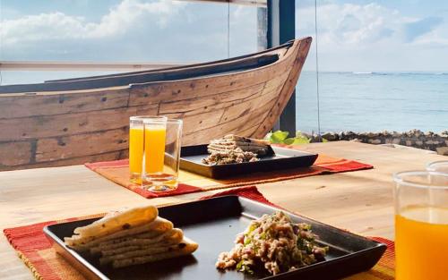 a table with two plates of food and a glass of orange juice at Tranquil Nest Vaavu in Rakeedhoo