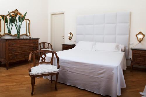 a bedroom with a white bed and a chair at Exclusive Aparthotel La Reunion in Ravenna
