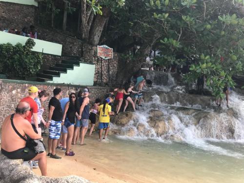 a group of people standing on the beach near a waterfall at Mystic Ridge Paradise in Ocho Rios