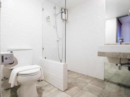 a white bathroom with a toilet and a shower at Loyy Hotel in Chiang Mai