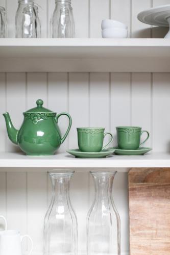 a shelf with two green cups and vases on it at Nest House Bright in Bright