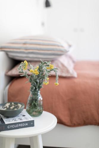 a vase with flowers on a table next to a bed at Nest House Bright in Bright
