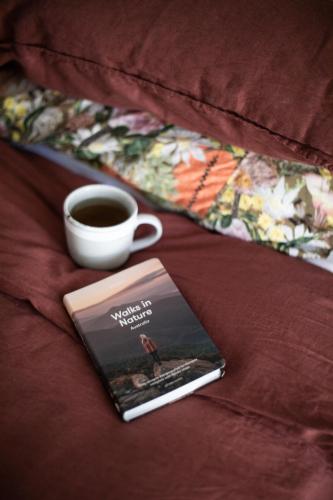 a book and a cup of coffee on a bed at Nest House Bright in Bright