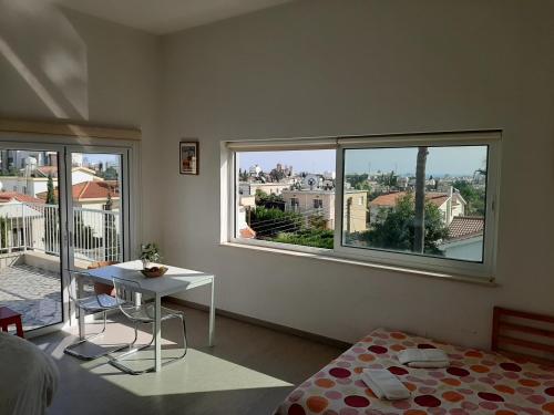 Cette chambre comprend un lit, une table et deux fenêtres. dans l'établissement Limassol sea view studio, à Limassol