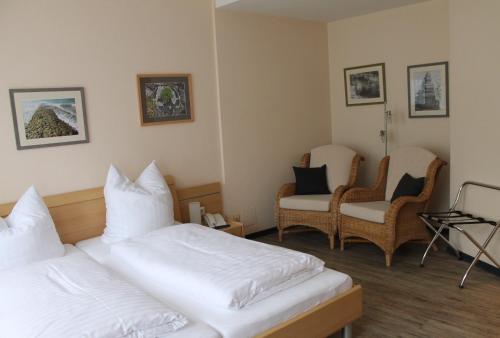 a hotel room with two beds and two chairs at Alleehotel-Eschen in Aurich