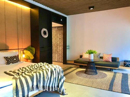 a bedroom with a bed and a table and a couch at Origin Ubud in Ubud
