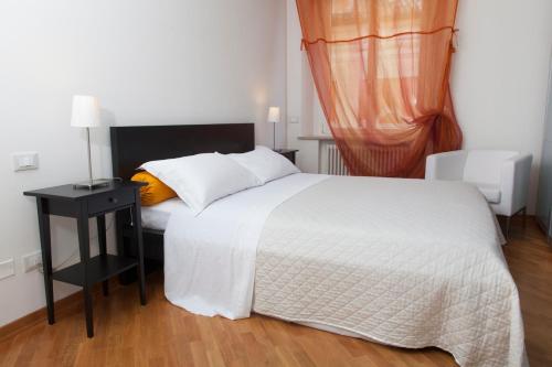 a bedroom with a white bed and a black night stand at Exclusive Aparthotel La Reunion in Ravenna