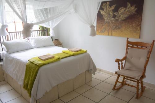 - une chambre avec un lit et une chaise dans l'établissement C-Mew Guest House, à Praia do Tofo