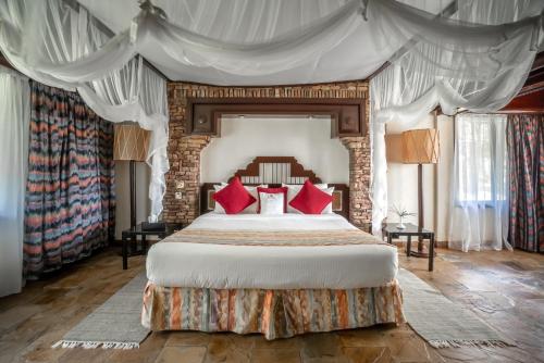 Sarova Shaba Game Lodge في Archers Post: غرفة نوم بسرير كبير ومخدات حمراء