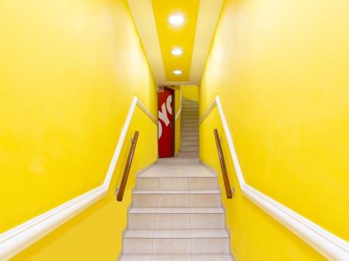 a staircase in a hallway with yellow walls and white stairs at Hotel Macuco in São Paulo