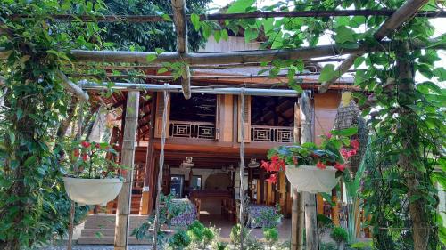 dom z dwoma doniczkami przed nim w obiekcie Mai Chau Dreams Homestay w mieście Mai Châu