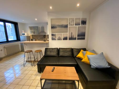 a living room with a black couch and a table at 09 CHIC & COSY GRAND APPART 4 PIÈCES 75m2 HYPERCENTRE WIFI SMART TV NETFLIX in Saint-Étienne