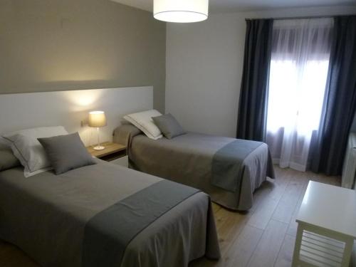 a hotel room with two beds and a window at Casa rural Villanueva in Mora de Rubielos