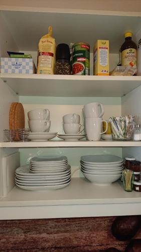 a shelf with plates and cups and dishes in a pantry at Wohnen im Kolonialstil inklusive Tiefgarage, kontaktloser Check-in in Klagenfurt