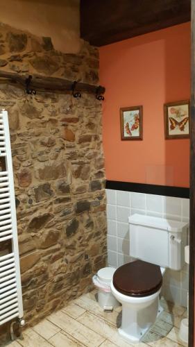 baño con aseo y pared de piedra en Dorinda, en Arganza