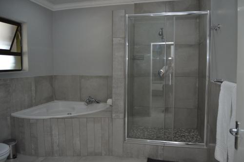 a bathroom with a shower and a tub and a sink at African Sands Guesthouse LOAD SHEDDING FREE in Bloemfontein
