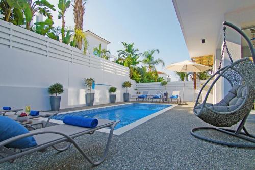 una piscina con sedie e un'altalena accanto a una casa di Villa Lily a Protaras