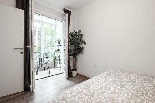 a white bedroom with a bed and a balcony at Periva Apartment Zagreb in Zagreb