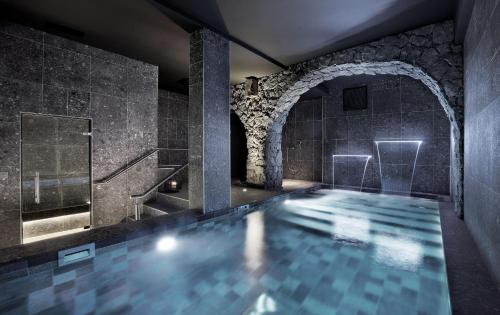 a swimming pool in a bathroom with a stone wall at Petit H&ocirc;tel Confidentiel in Chamb&eacute;ry