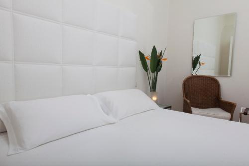 a white bedroom with a white bed and a chair at Exclusive Aparthotel La Reunion in Ravenna