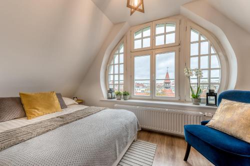 ein Schlafzimmer mit einem großen Fenster, einem Bett und einem Stuhl in der Unterkunft Apartamenty Katrin Home in Toruń