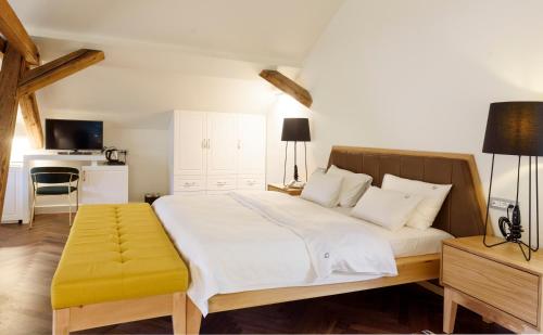 a bedroom with a large white bed with a yellow stool at Hotel Gradska Cetinje in Cetinje