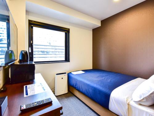岡山市にあるホテルリブマックス岡山WESTのベッド、デスク、コンピュータが備わるホテルルームです。