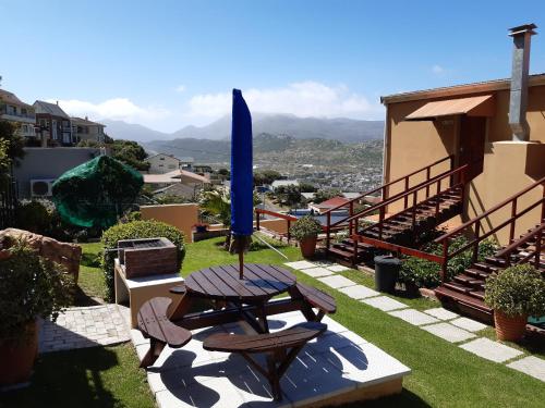 a patio with a table and a blue umbrella at A Place in Thyme in Fish hoek