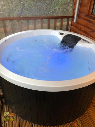 a hot tub on a deck with blue water at Cherry Tree Glamping in Stroud