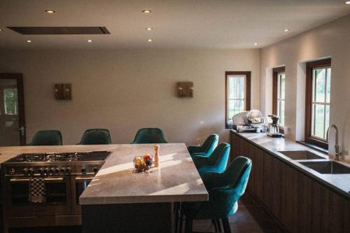 a kitchen with a stove and a counter with chairs at The Annex Retreat - a luxury countryside villa in Geijsteren