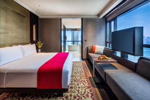 a hotel room with a bed and a couch and a tv at Regent Chongqing in Chongqing