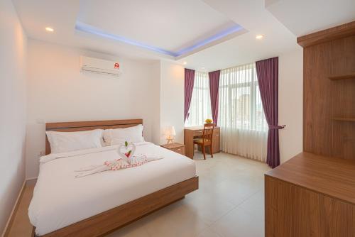 a bedroom with a large white bed and a desk at Queen Mansion in Phnom Penh