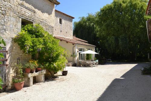 un edificio con plantas, una mesa y una sombrilla en Le Moulin de Lusseau, en Chef-Boutonne