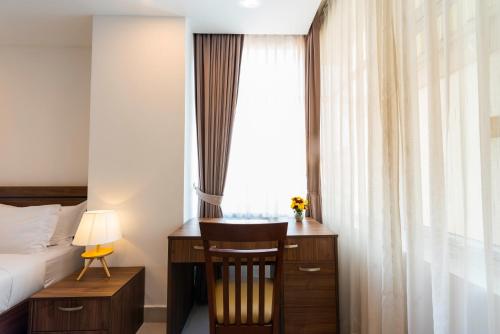 a bedroom with a bed and a desk and a window at Queen Mansion in Phnom Penh