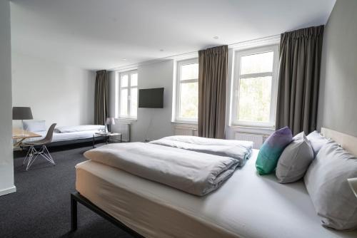 a hotel room with two beds and a desk at BIG MAMA Leipzig in Leipzig