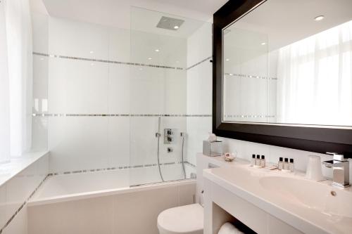 a white bathroom with a sink and a mirror at Grand Hôtel Thalasso & Spa in Saint-Jean-de-Luz