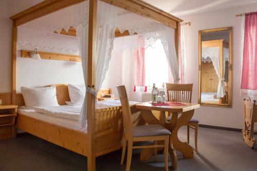 Burgthann的住宿－Weißer Löwe，一间卧室配有一张带桌子的天蓬床和一间餐厅