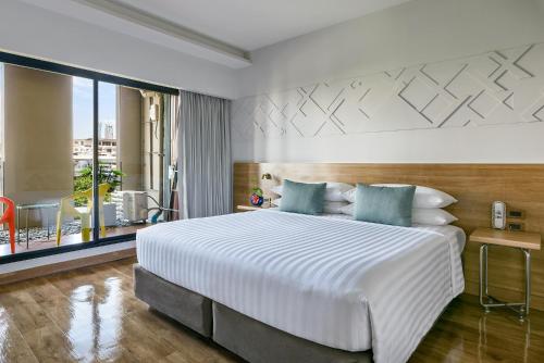 a bedroom with a large white bed and a balcony at VELA be Bangkok Ratchathewi in Bangkok